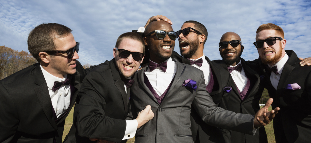 Wedding party wearing coordinated suits and purple bow ties
